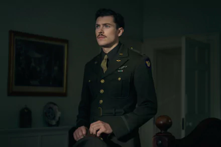 HD wallpaper of an intense scene from the TV show Masters of the Air featuring a military officer in uniform standing thoughtfully in a dimly lit room.