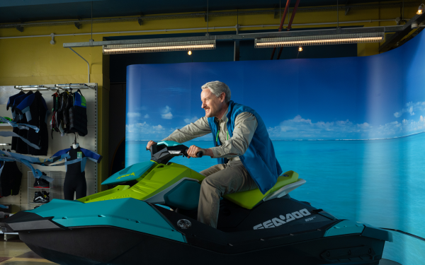 HD desktop wallpaper featuring a male character on a jet ski simulator with a vibrant beach background, tagged with Loki and Owen Wilson themes.