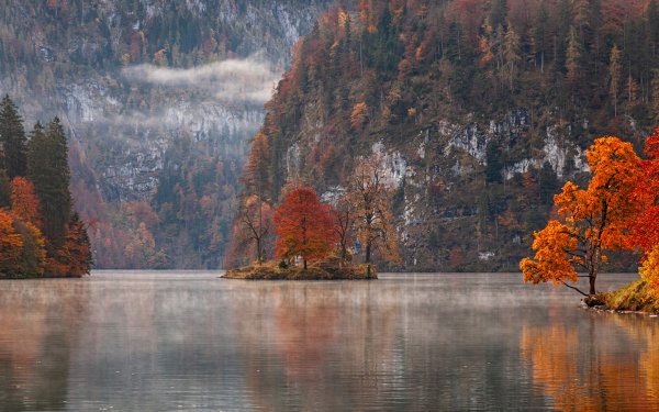 Autumn scenery HD desktop wallpaper featuring a serene lake with vibrant orange trees and a misty mountain backdrop.