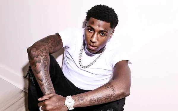 Alt Text: HD wallpaper of a young male artist with tattoos sitting down, representing YoungBoy Never Broke Again, with a music theme for desktop backgrounds.