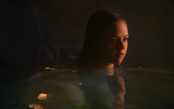 HD wallpaper of a serene night swim scene from a movie, featuring a person submerged in water with a contemplative expression.