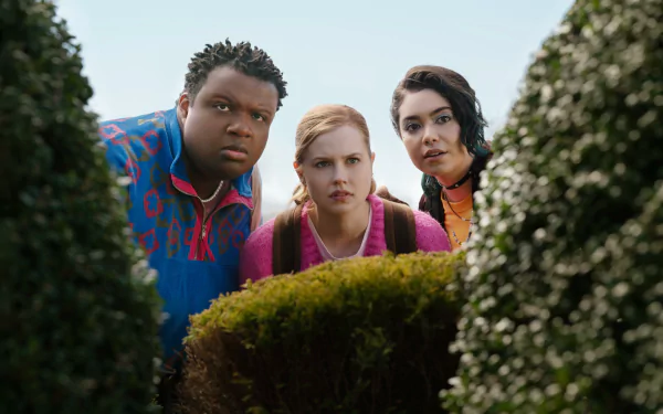 Three characters from Mean Girls (2024) peek through bushes, displaying curious expressions. This image serves as an engaging HD desktop wallpaper and background.