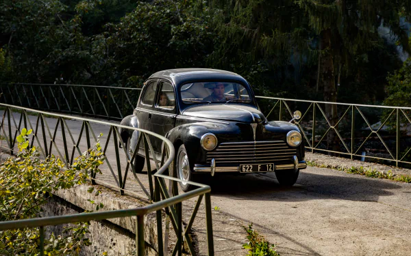 Vintage car from TV Show Monsieur Spade crossing a bridge in a serene woodland setting, suitable as a HD desktop wallpaper and background.