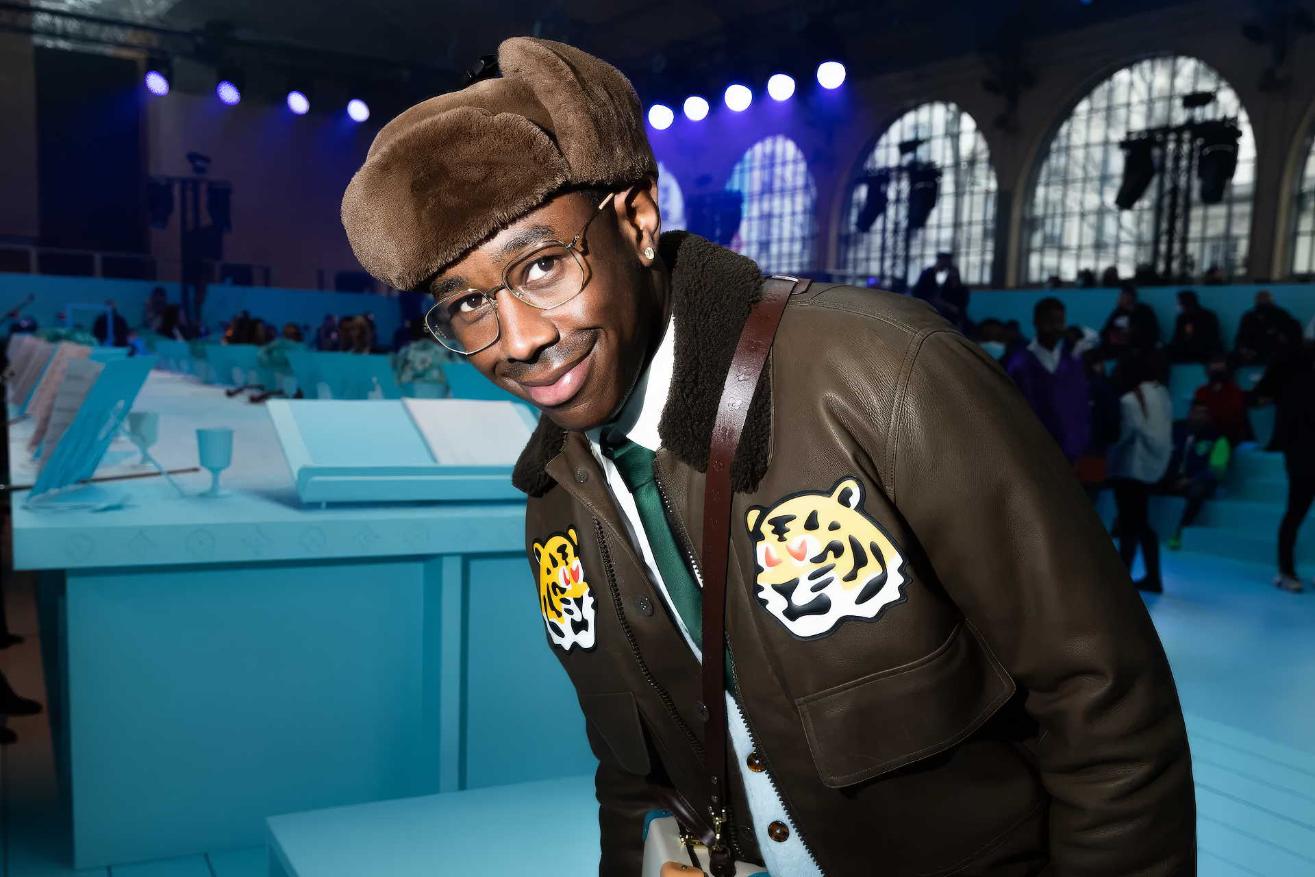 HD desktop wallpaper featuring a stylish individual at an event, evoking the creative spirit of music artist Tyler, the Creator.