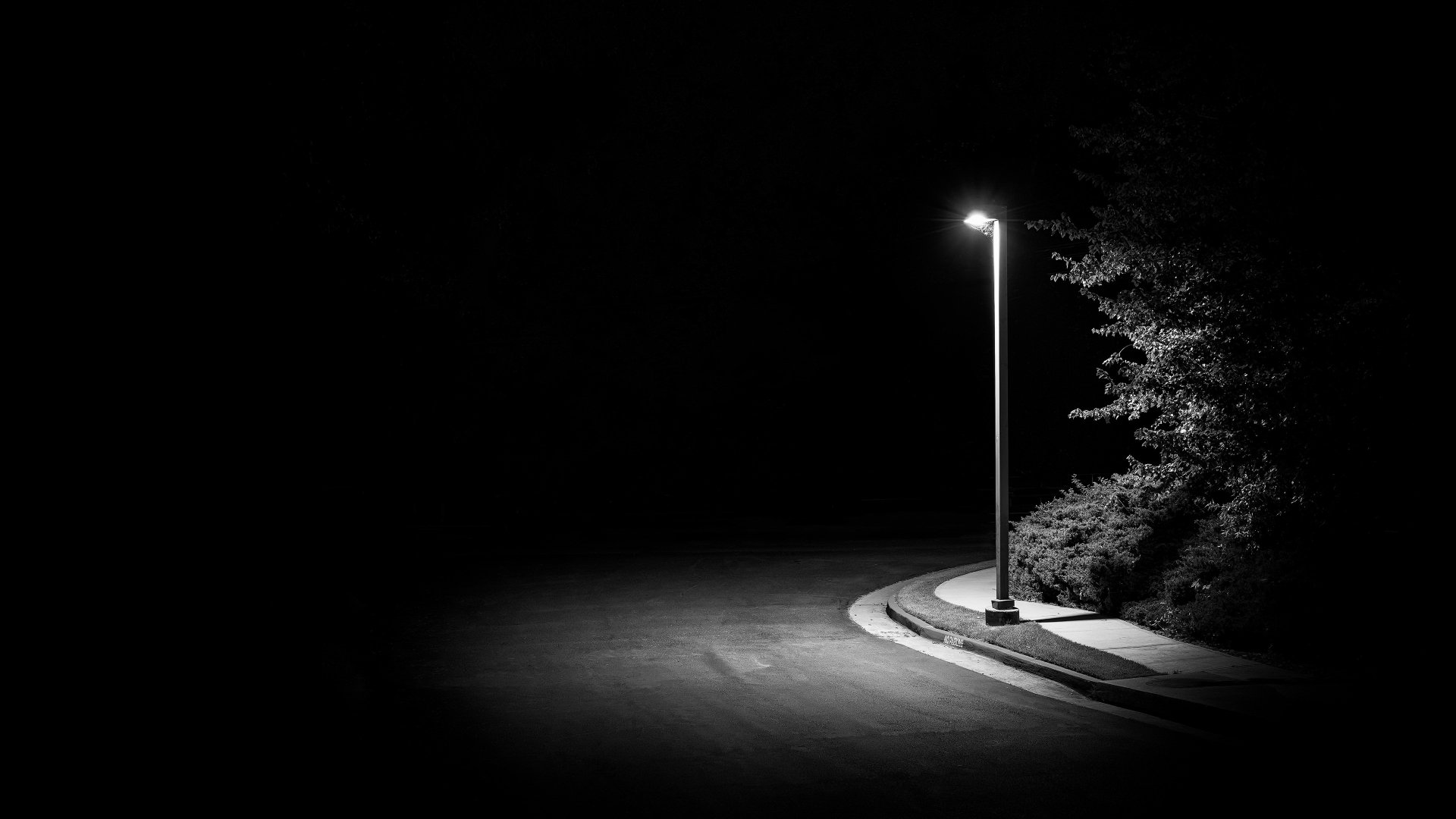 A 4K Ultra HD PC desktop wallpaper featuring a solitary streetlamp illuminating a quiet, curved sidewalk at night with surrounding trees in deep shadows.