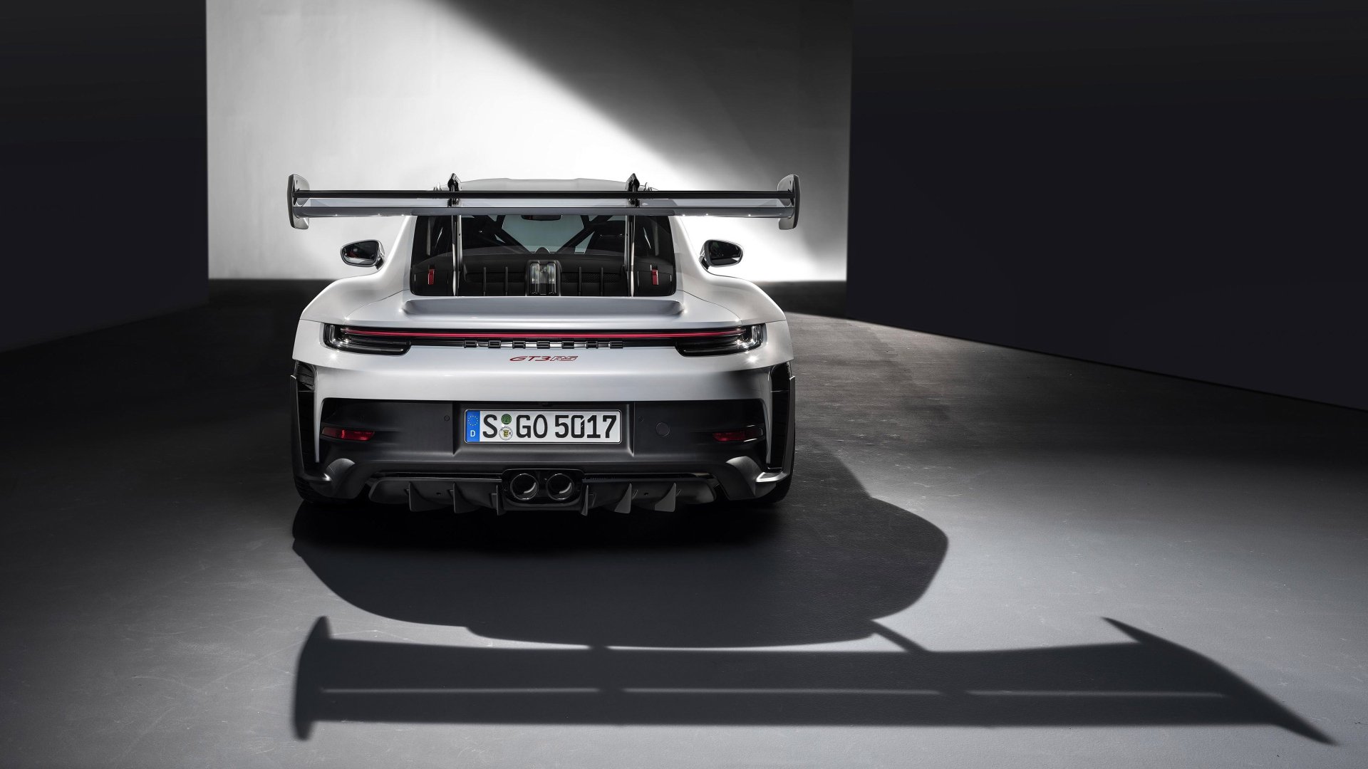 HD desktop wallpaper featuring a rear view of a Porsche 911 GT3 RS, highlighted under dramatic lighting.