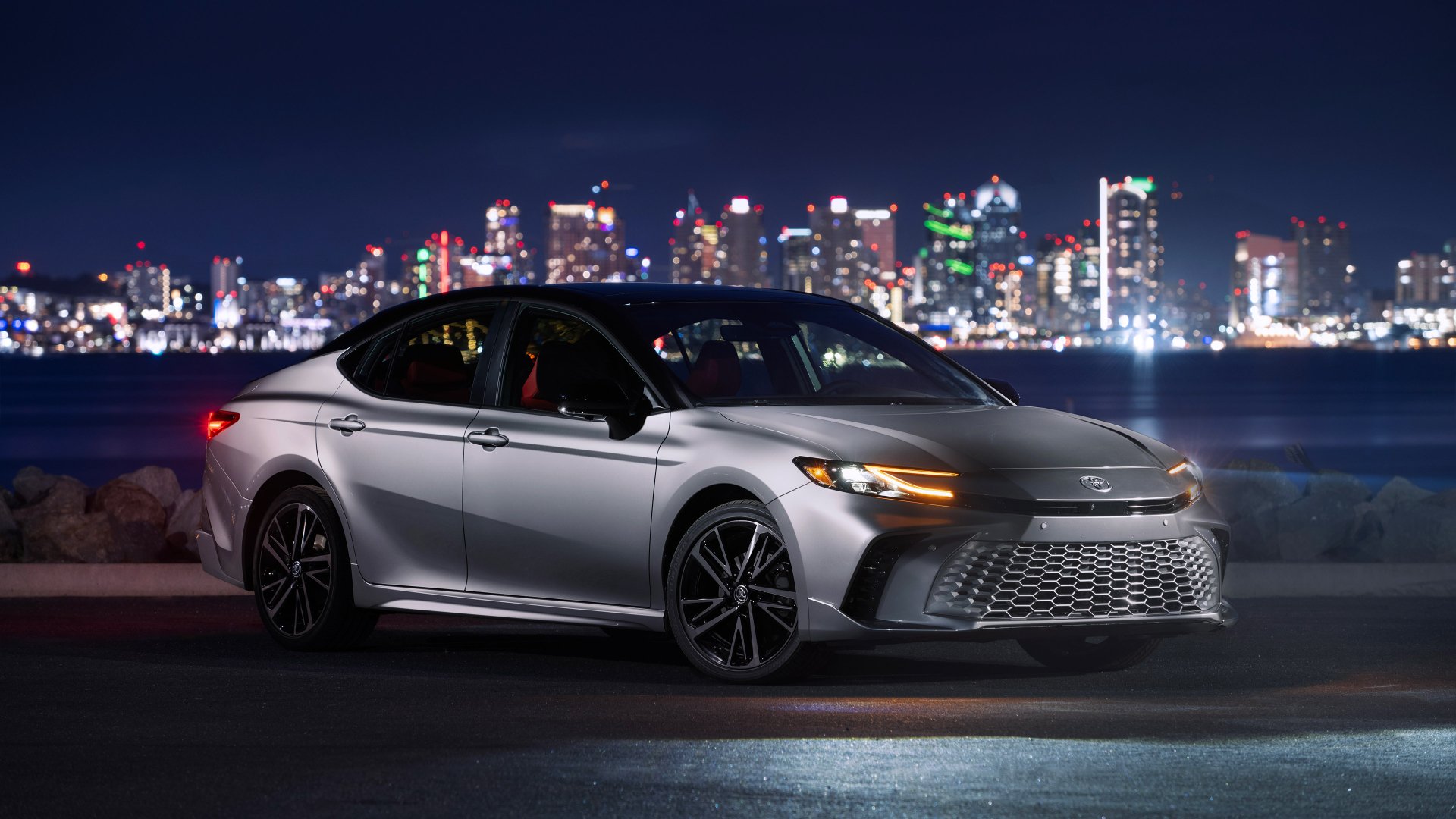 A Toyota Camry XSE parked with a vibrant cityscape in the background, serving as a sleek HD wallpaper.