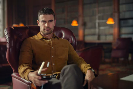 A striking HD wallpaper from the TV show The Gentlemen (2024) featuring Theo James seated in a luxurious armchair, holding a drink with a confident expression.