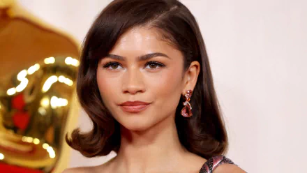 Zendaya poses elegantly at the Academy Awards (Oscars), showcasing her glamorous style against a backdrop featuring the iconic Oscar statue. HD desktop wallpaper.