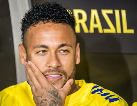Soccer star in Brazil jersey posing thoughtfully for an HD desktop wallpaper background.