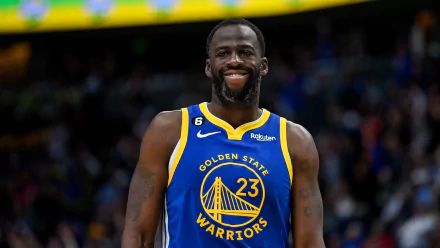 HD desktop wallpaper of Draymond Green in his Golden State Warriors jersey, smiling on the basketball court.