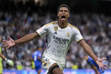 A soccer player in a Real Madrid C.F. kit celebrating on the field with an expressive gesture, captured in a high-definition desktop wallpaper.