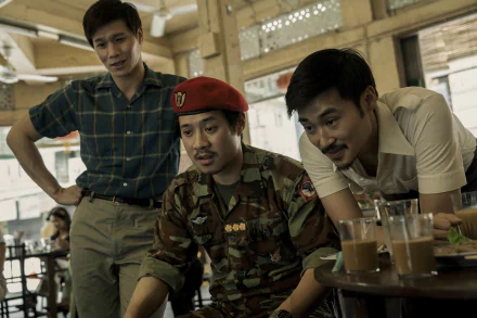 A scene from the TV show The Sympathizer featuring three characters in a cafe, one wearing a military uniform with a red beret, as they engage in conversation, presented as a high-definition desktop wallpaper.