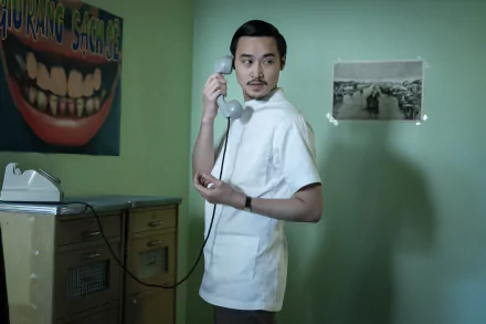HD wallpaper from The Sympathizer TV show featuring a character speaking on the phone in a retro-themed room.