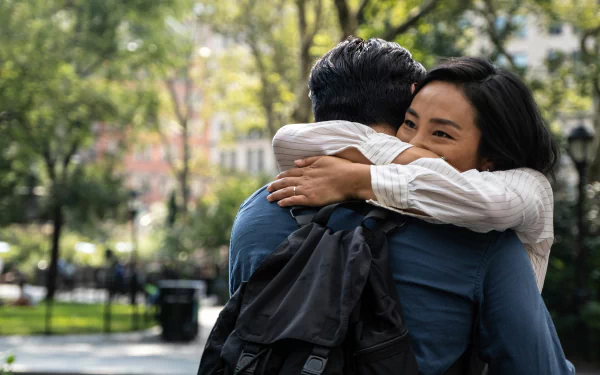 HD wallpaper of a scene from the movie Past Lives featuring two individuals embracing in a heartfelt hug at a park.