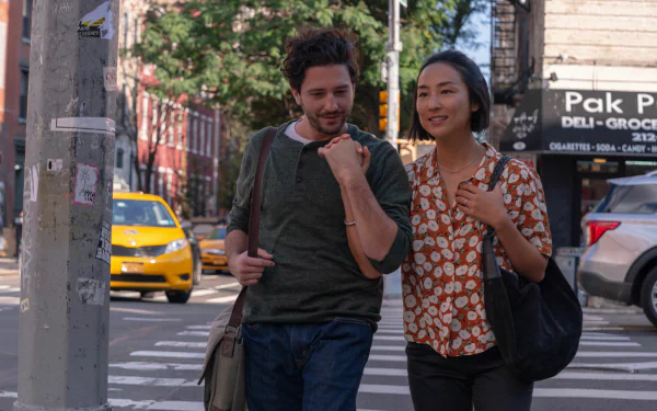 HD wallpaper showing a scene from the movie Past Lives featuring a man and a woman walking together on a city street, casually dressed and engaged in conversation, with a yellow taxi in the background.