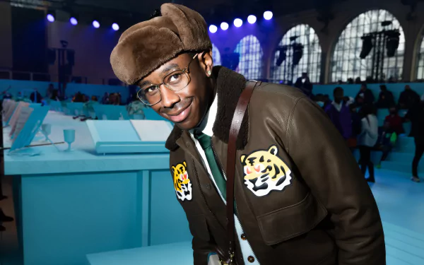 HD desktop wallpaper featuring a stylish individual at an event, evoking the creative spirit of music artist Tyler, the Creator.