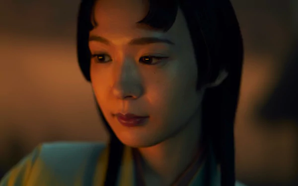 HD wallpaper of Shogun 2024 TV show featuring a close-up of a female character with a contemplative expression, set against a warm, dimly lit background.