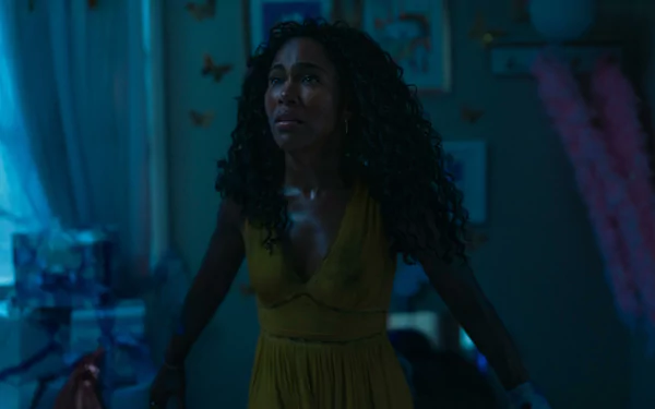 A scene from the movie *Imaginary (2024)* featuring DeWanda Wise, showing her with curly hair in a yellow dress, set in a softly lit room adorned with decorations.