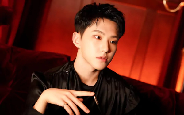 HD wallpaper featuring RM from BTS, captured in a striking pose against a warm, dramatic backdrop, showcasing his unique style and charisma.