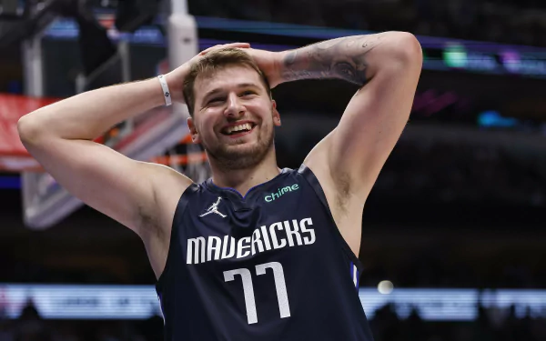 HD wallpaper featuring a Dallas Mavericks basketball player on the court wearing a jersey with the number 77, expressing a moment of emotion during a game.