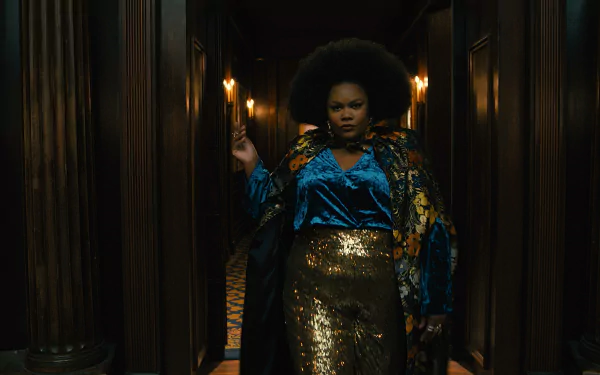 A striking scene from the TV show The American Society of Magical Negroes, featuring a confident figure in a vibrant outfit, set in a dimly lit corridor adorned with warm lighting.
