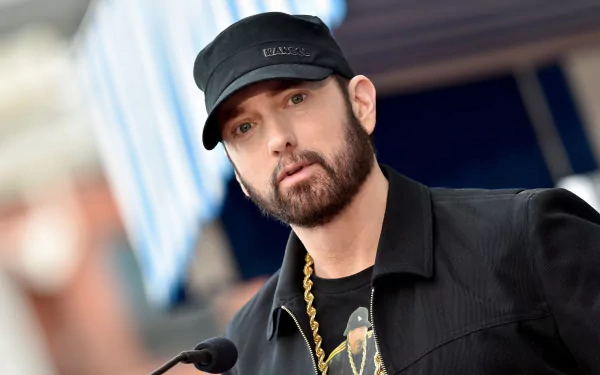 Hip-hop artist with black cap and beard posing for an HD rapper music desktop wallpaper background.