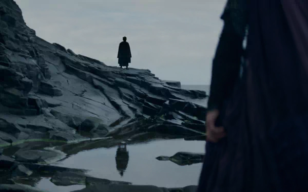 HD wallpaper featuring a scene from the TV show The Acolyte (2024) with a mysterious figure standing on a rocky landscape reflected in water.