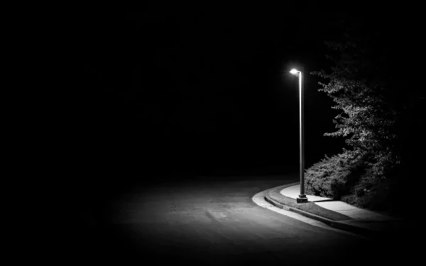 A 4K Ultra HD PC desktop wallpaper featuring a solitary streetlamp illuminating a quiet, curved sidewalk at night with surrounding trees in deep shadows.