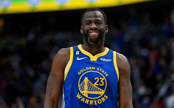 HD desktop wallpaper of Draymond Green in his Golden State Warriors jersey, smiling on the basketball court.