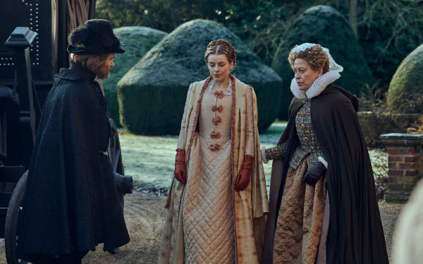 HD desktop wallpaper of three characters from the TV show Mary & George conversing in a historical setting with manicured hedges in the background.