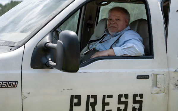 A man sitting in the driver's seat of a white vehicle with the word PRESS on the door, possibly portraying a character in a movie related to a Civil War theme. The image serves as a high-definition desktop wallpaper.