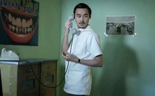 HD wallpaper from The Sympathizer TV show featuring a character speaking on the phone in a retro-themed room.