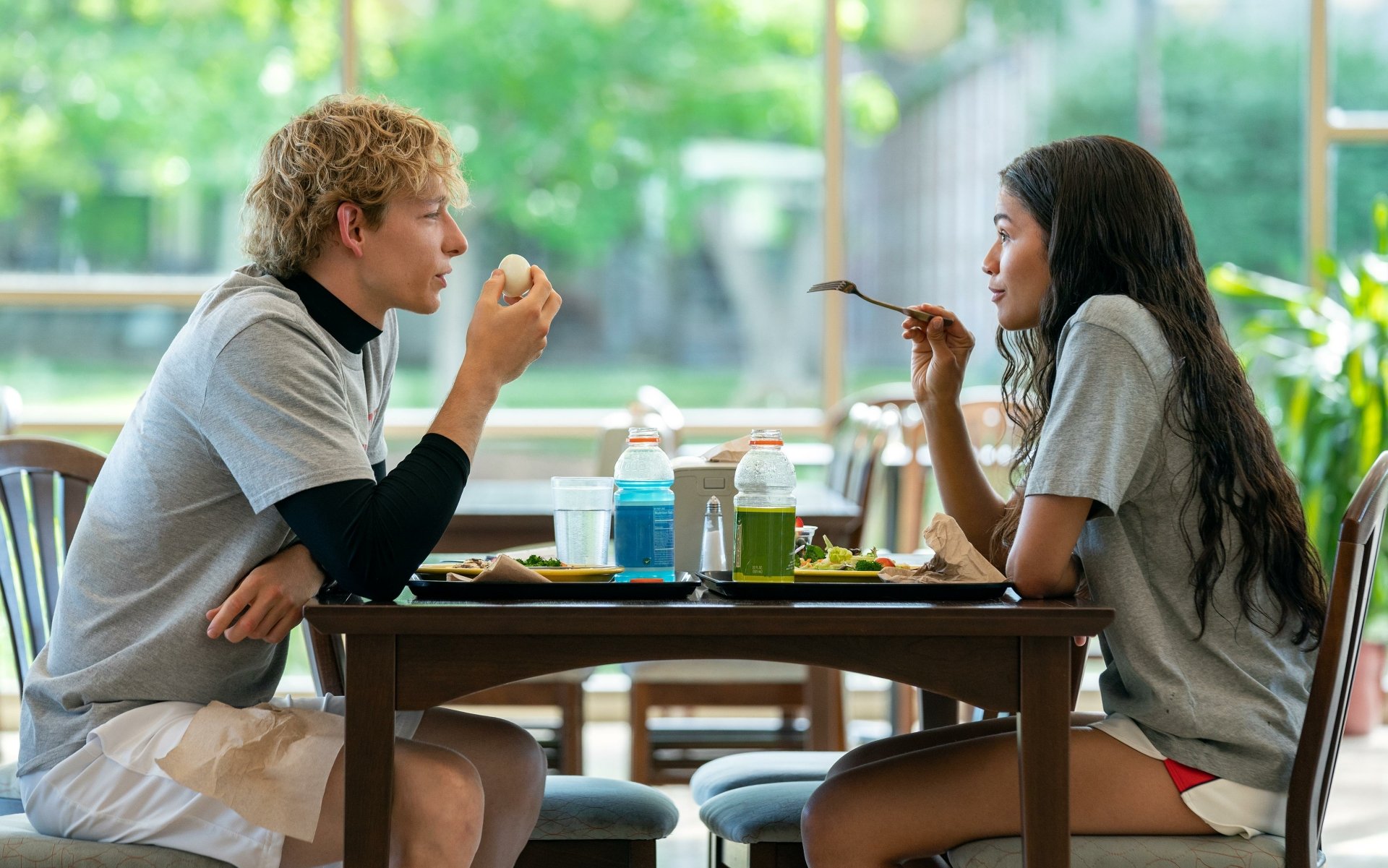 HD desktop wallpaper from Challengers (2024) featuring a young man and woman eating and talking at a cafeteria table.