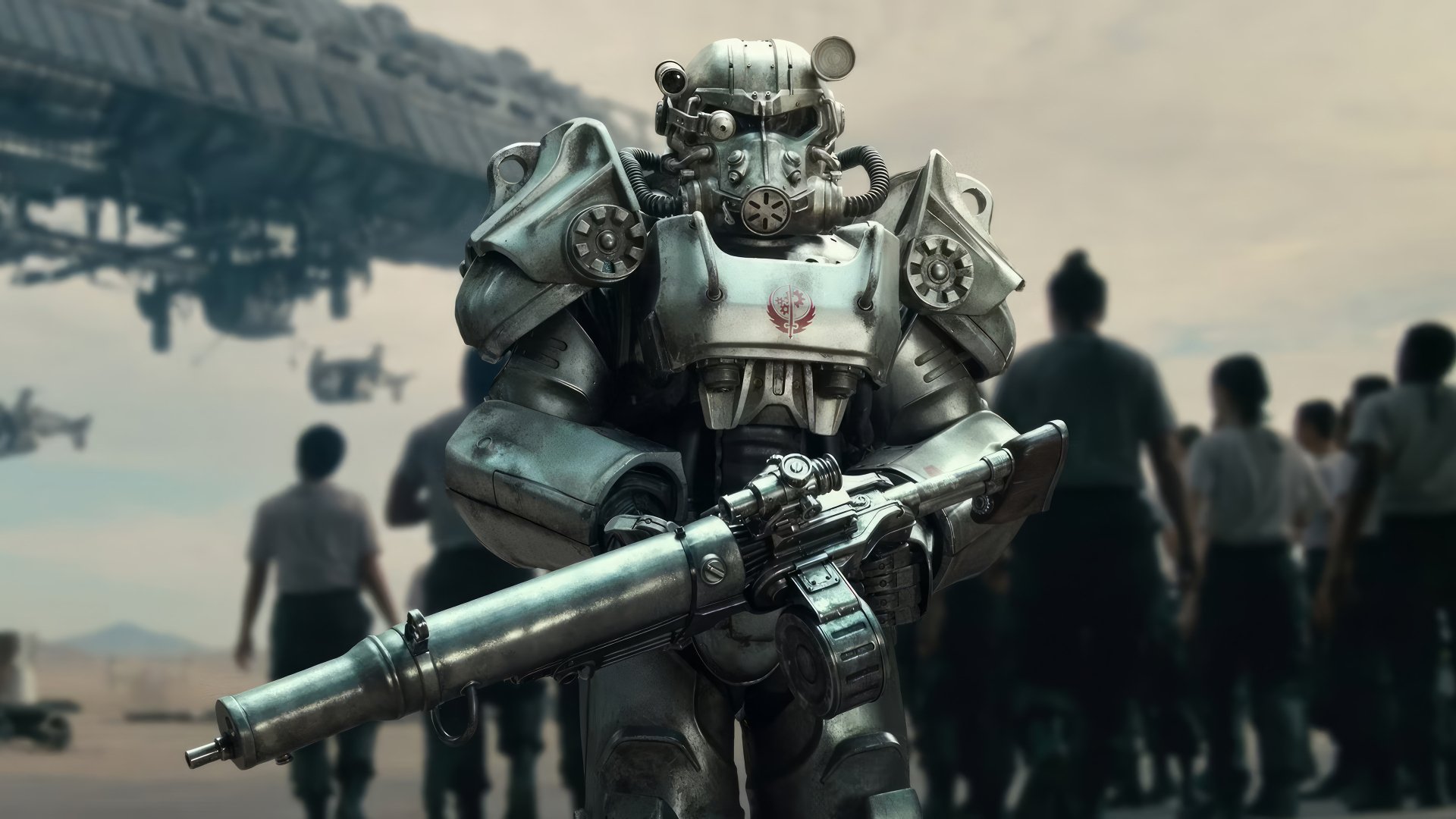 HD desktop wallpaper of a character in power armor from the Fallout TV show, standing in a desolate setting with people and structures in the background.