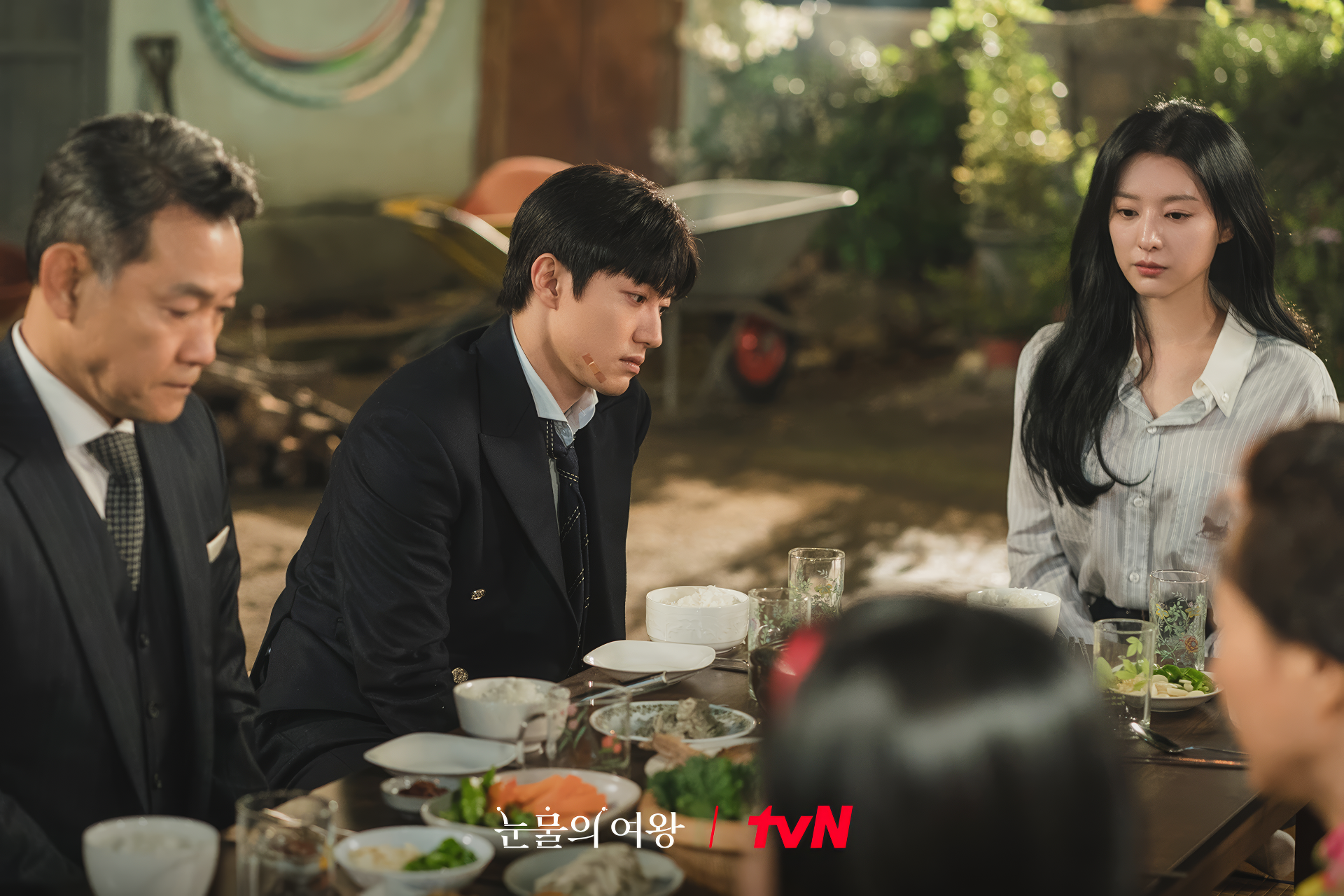 HD wallpaper featuring a scene from the TV show Queen of Tears with three characters at a dining table, displaying the tvN logo.