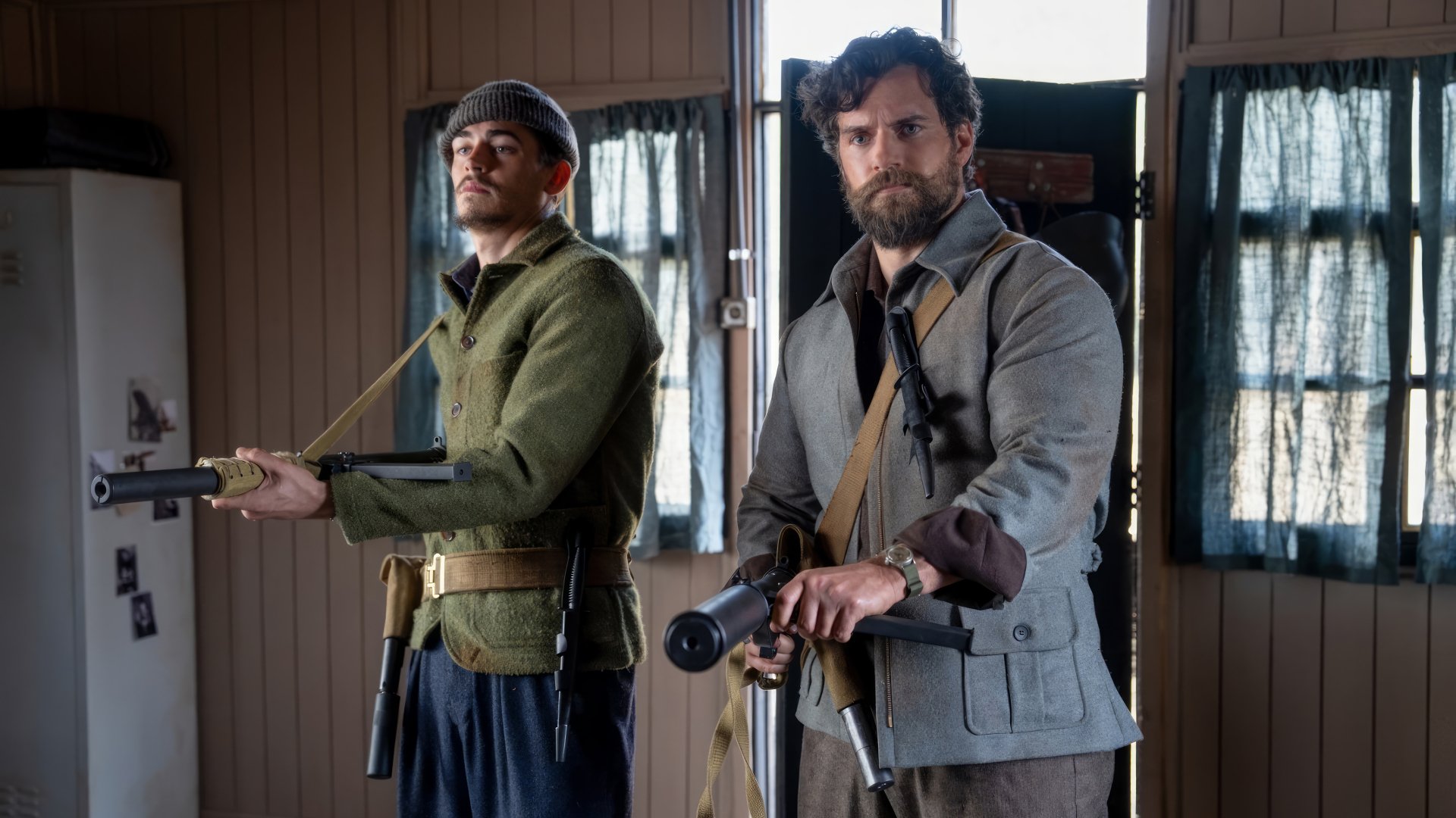 HD wallpaper from The Ministry of Ungentlemanly Warfare featuring Henry Cavill, showing two characters armed and focused in a vintage interior.