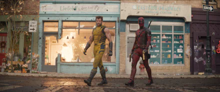 A vibrant HD desktop wallpaper featuring Wolverine and Deadpool walking confidently in front of a storefront, capturing their iconic dynamic from the movie universe.