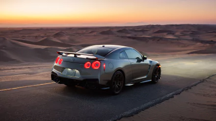 HD wallpaper of a Nissan GT-R parked on a desert road at sunset, showcasing its sleek design and glowing tail lights.