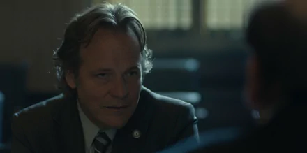 HD desktop wallpaper featuring Peter Sarsgaard in a scene from the TV show Presumed Innocent (2024). The image captures a contemplative moment with a blurred background adding depth to the setting.