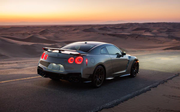 HD wallpaper of a Nissan GT-R parked on a desert road at sunset, showcasing its sleek design and glowing tail lights.