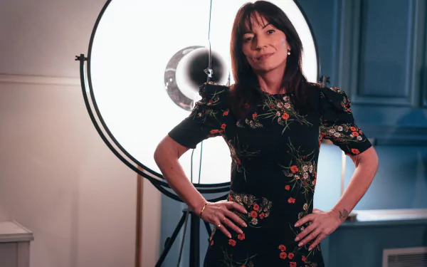 HD wallpaper from Doctor Who (2023) featuring a confident woman in a floral dress standing in a lit studio.