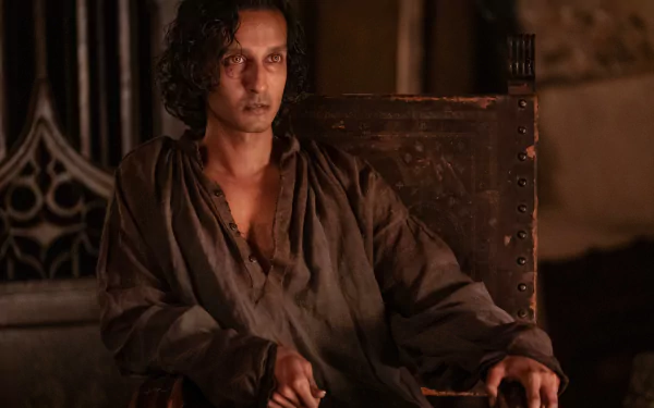 Alt Text: High-definition wallpaper featuring a character from the TV show Interview with the Vampire, seated in a dim, ornate room, exuding a mysterious aura.