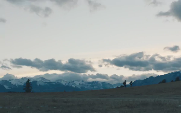 The Last Of Us 8K Ultra HD PC desktop wallpaper featuring a vast open field with distant mountains under a cloudy sky at dusk.