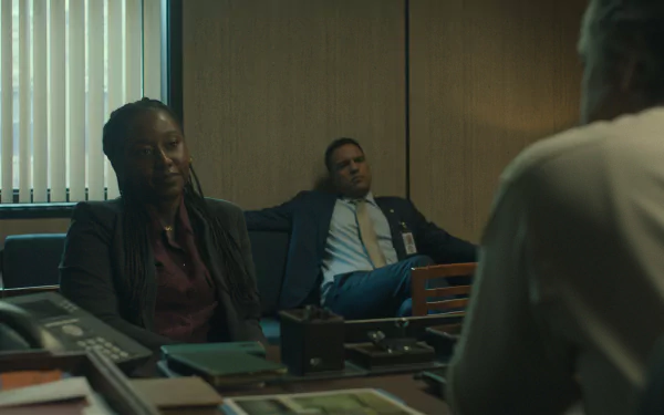 Scene from the TV show Presumed Innocent (2024) showing three people in a dimly lit office, with two sitting opposite another. The image is an HD desktop wallpaper and background.