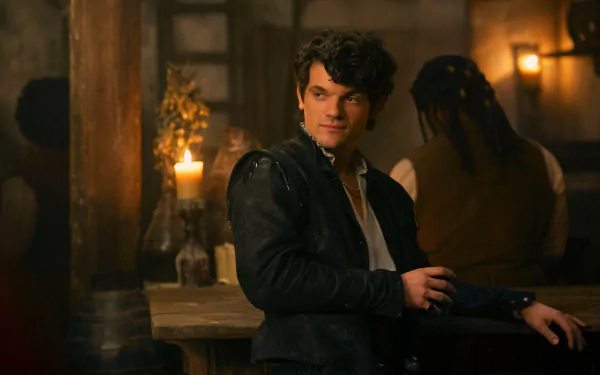 A scene from the movie My Lady Jane featuring a young man in historical attire, leaning against a bar in a dimly lit room. HD desktop wallpaper and background.