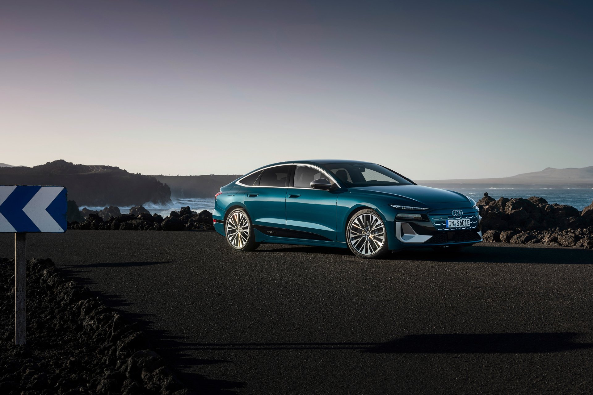 A stunning Audi S6 E-Tron parked on a scenic road, surrounded by rocky terrain and a tranquil sea backdrop, showcased as a high-definition desktop wallpaper.