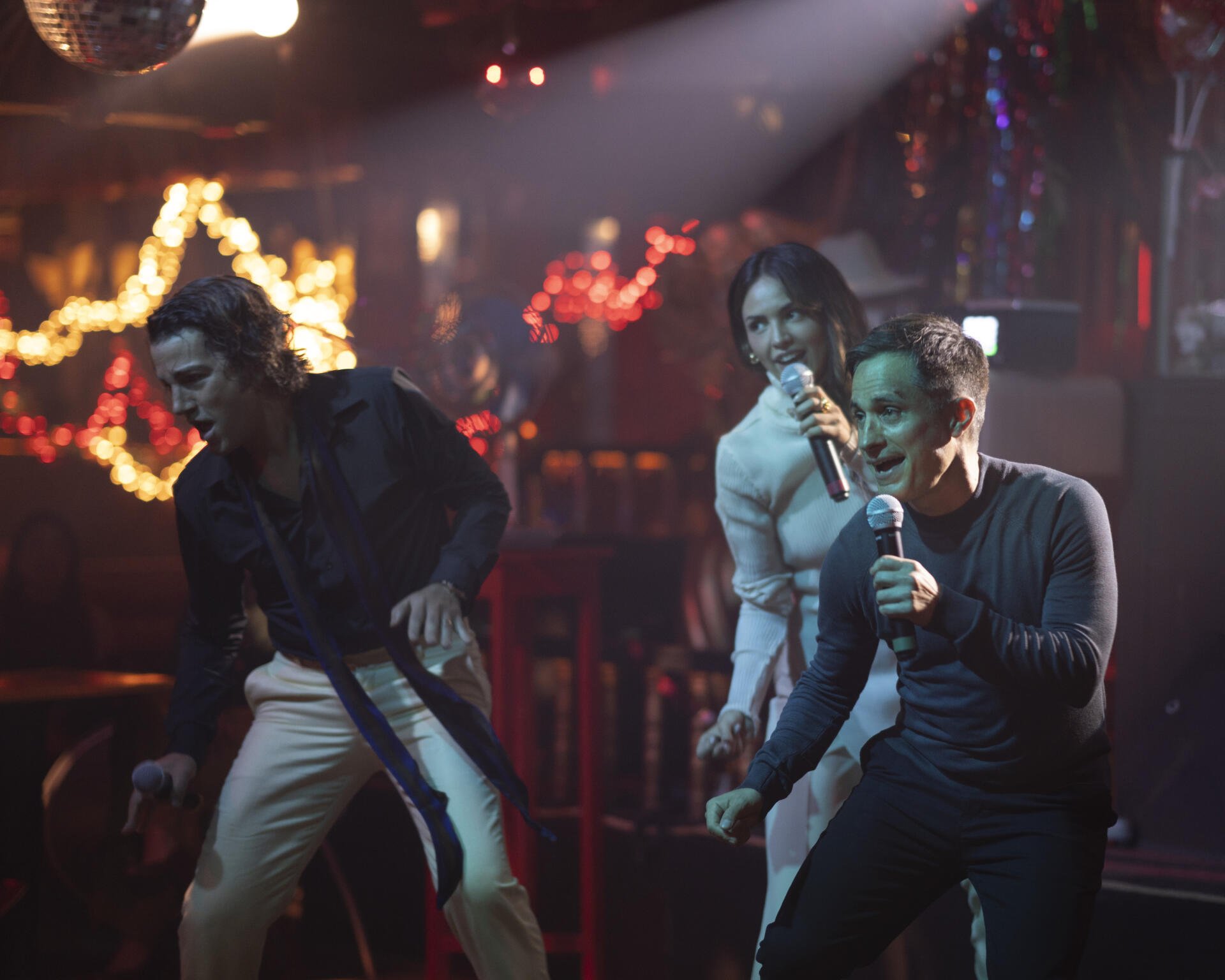 Dynamic scene from the TV show La Máquina (2024) featuring performers singing passionately on stage in a vibrant, illuminated setting.