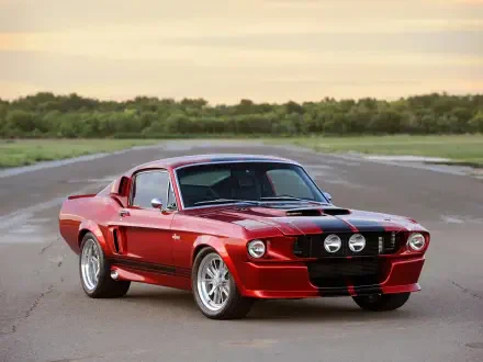 A classic Shelby GT500CR, showcasing its sleek red design, parked on an open road with a scenic background, captures the essence of vintage American muscle cars.