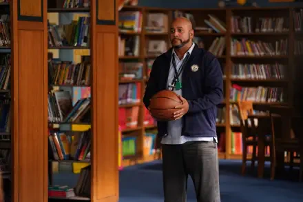 A scene from the TV show *Abbott Elementary*, featuring a character holding a basketball in a library filled with books, creating a vibrant educational atmosphere.
